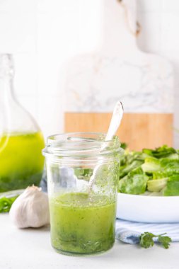 Mutfak aromalı yeşil sebze salatası sosu. Akşam yemeği için maydanoz sarımsaklı zeytinyağı ve mutfak arka planında yeşil salata.