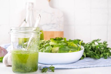 Mutfak aromalı yeşil sebze salatası sosu. Akşam yemeği için maydanoz sarımsaklı zeytinyağı ve mutfak arka planında yeşil salata.