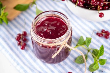 Mutfak masasında taze böğürtlen bulunan küçük kavanozdaki organik kırmızı frenk üzümü reçeli ya da marmelat.