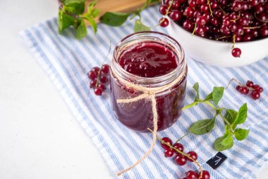 Mutfak masasında taze böğürtlen bulunan küçük kavanozdaki organik kırmızı frenk üzümü reçeli ya da marmelat.