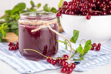 Mutfak masasında taze böğürtlen bulunan küçük kavanozdaki organik kırmızı frenk üzümü reçeli ya da marmelat.