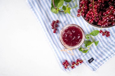Mutfak masasında taze böğürtlen bulunan küçük kavanozdaki organik kırmızı frenk üzümü reçeli ya da marmelat.