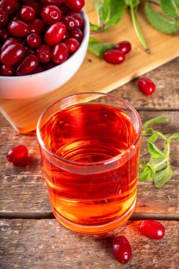 Cornelian kirazı, kızılcık, yenilebilir meyve suyu ya da bardakta likör, ahşap masa arkasında, nane ve taze mısır gevreği fotokopi alanı.