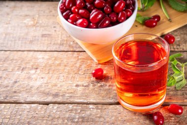 Cornelian kirazı, kızılcık, yenilebilir meyve suyu ya da bardakta likör, ahşap masa arkasında, nane ve taze mısır gevreği fotokopi alanı.