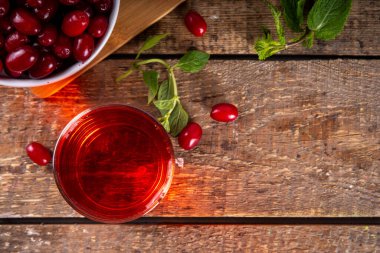 Cornelian kirazı, kızılcık, yenilebilir meyve suyu ya da bardakta likör, ahşap masa arkasında, nane ve taze mısır gevreği fotokopi alanı.