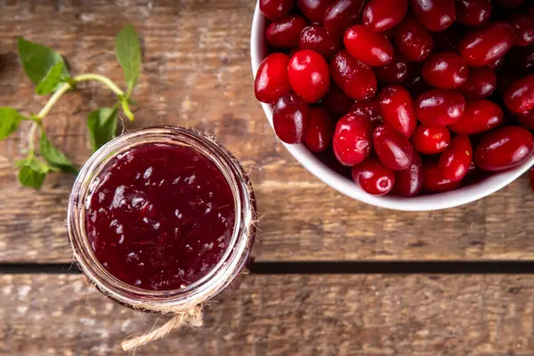 stock image Cornelian cherry, dogwoods edible berry jam or marmalade in small jar with fresh berries on wooden table, copy space