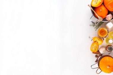 Balkabağı pişirme arka planı dilimlenmiş balkabağı yarımları ya da tereyağlı kabak, çiğ otlar. Beyaz arka planda kesim tahtası, bitki ve bal içeren baharatlar. Şükran Günü yemeği mevsimlik yemek