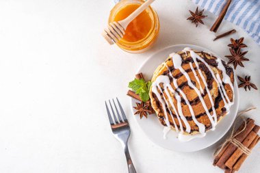 Ev yapımı tarçınlı krep yığını, tarçınlı krep sarmalı tarçın ve krem peynirli jöle, beyaz mutfak masası, fotokopi masası.