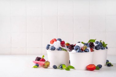 Çeşit çeşit çilek soslu donmuş yoğurt tatlısı. Ahududu, çilek, yaban mersini ve naneli kremalı yoğurtlu dondurma.