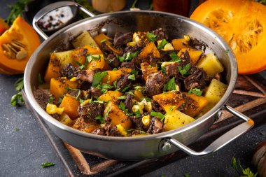 Sıcak balkabağı güveci patates ve sığır eti, konforlu sonbahar yemeği dengeli yemek, mutfak masasında malzemeler