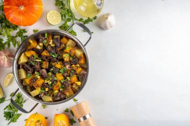 Sıcak balkabağı güveci patates ve sığır eti, konforlu sonbahar yemeği dengeli yemek, mutfak masasında malzemeler
