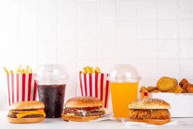 Fast food servis menüsünde çeşitli hamburgerler, cheeseburger, nugget, patates kızartması, gazlı içecek. Ivır zıvır sağlıksız fast food, düşük besinli Ultra işlenmiş gıda, yüksek kalori değeri