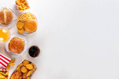 Fast food servis menüsünde çeşitli hamburgerler, cheeseburger, nugget, patates kızartması, gazlı içecek. Ivır zıvır sağlıksız fast food, düşük besinli Ultra işlenmiş gıda, yüksek kalori değeri