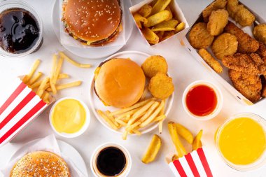 Fast food servis menüsünde çeşitli hamburgerler, cheeseburger, nugget, patates kızartması, gazlı içecek. Ivır zıvır sağlıksız fast food, düşük besinli Ultra işlenmiş gıda, yüksek kalori değeri