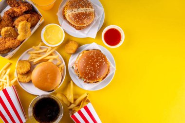 Fast food servis menüsünde çeşitli hamburgerler, cheeseburger, nugget, patates kızartması, gazlı içecek. Ivır zıvır sağlıksız fast food, düşük besinli Ultra işlenmiş gıda, yüksek kalori değeri