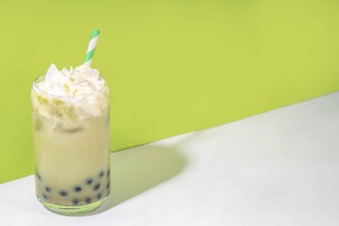 Tapyoka incili yeşil kibrit boba çayı. Koyu tapyoka topları ve sütsüz krem şantili Asya usulü buzlu içecek, boşluğu kopyala