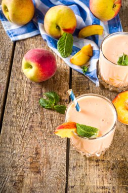 Yaz kahvaltısı içeceği, taze şeftalili smoothie, şeftalili yoğurt nektarin dilimleri, kırsal ahşap arka plan fotokopi alanı.