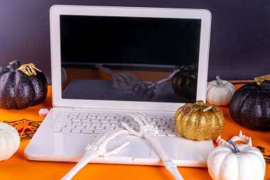 Düz dizüstü bilgisayarı olan komik bir Cadılar Bayramı çalışma yeri. Ofis şirketi Cadılar Bayramı partisi davetiyesi, blog yazarı sonbahar tatili geçmişi. Cadılar Bayramı parti dekorlu beyaz laptop, turuncu arka plan manzaralı