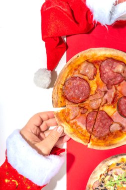 Pepperoni ve mantarlı pizza, Noel Baba eli pizza dilimi alır. Teslimat ve restoran Xmas öğle yemeği ve parti menüsü, Noel Baba Noel için pizza dağıtıyor, beyaz kırmızı, yüksek renkli arka plan