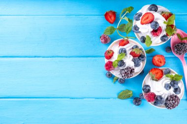 Çeşit çeşit çilek soslu donmuş yoğurt tatlısı. Ahududu, çilek, yaban mersini ve naneli kremalı yoğurtlu dondurma.