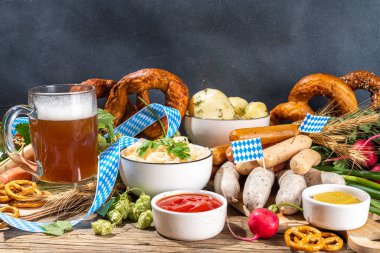 Oktoberfest holiday greeting card, menu, invitation background, Traditional Oktoberfest festival food, bavarian sausages, pretzels, potato, sauerkraut, beer mug on wooden background, copy space above