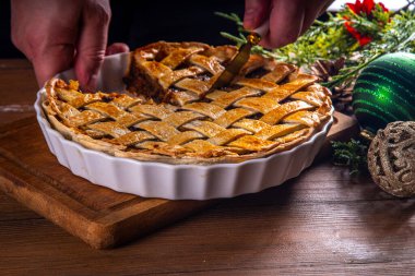 Geleneksel İngiliz Noel turtası. Ev yapımı tatlı kıymalı tart kek, baharatlı meyve, fındık ve elmalarla dolu, rahat ahşap masa üzerinde Noel ağacı ve süslemesi ile