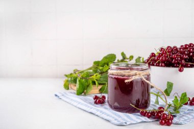 Mutfak masasında taze böğürtlen bulunan küçük kavanozdaki organik kırmızı frenk üzümü reçeli ya da marmelat.