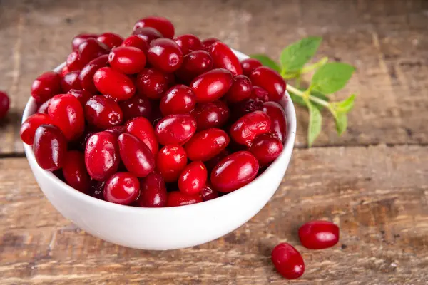 stock image Cornelian cherry, dogwoods edible berry in white bowl on kitchen table copy space