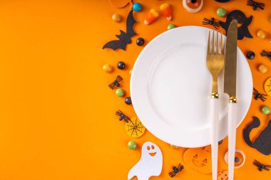 Cadılar Bayramı çocuklarının masa takımları tabak, çatal bıçak takımı ve bayram sembolleri ve renkli arka plan süslemeleri ile üst görünüm fotokopi alanı. Cadılar Bayramı menüsü, davet arkaplanı