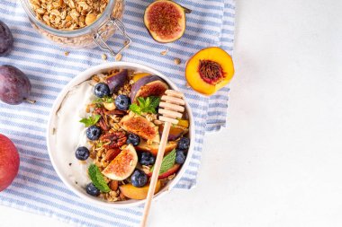 Sağlıklı sonbahar kahvaltı kasesi. Süzme peynir veya yoğurtlu granola, fındık ve sonbahar meyveleri, sabah ve öğle yemekleri için dengeli atıştırmalık, fotokopi alanı. 