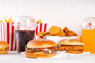 Fast food servis menüsünde çeşitli hamburgerler, cheeseburger, nugget, patates kızartması, gazlı içecek. Ivır zıvır sağlıksız fast food, düşük besinli Ultra işlenmiş gıda, yüksek kalori değeri