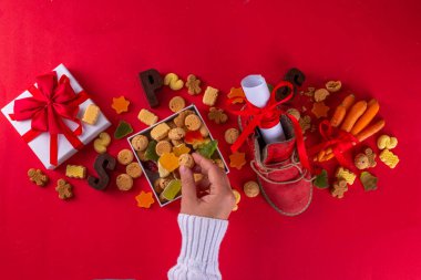 Sinterklaas, Aziz Niklas Günü geçmişi. Havuçlu ve şekerli kırmızı ayakkabılı küçük çocuk, trooigoed, pepernoten, şeker. Hollanda Noel tebrik kartı 