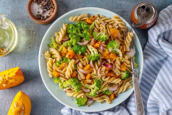 Balkabağı ve brokoli vejetaryen sıcak makarna salatası, sonbahar salatası, sonbahar konforu rahat yemek konsepti. 