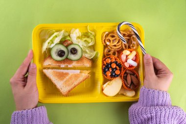 Cadılar Bayramı komik çocuklar, krakerli okul yemeği, sağlıklı peynirli sandviç, kurabiye ve ikramlar, parlak renkli arka plan fotokopi alanı üst görünümü.