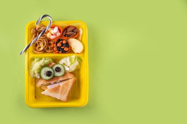 Cadılar Bayramı komik çocuklar, krakerli okul yemeği, sağlıklı peynirli sandviç, kurabiye ve ikramlar, parlak renkli arka plan fotokopi alanı üst görünümü.