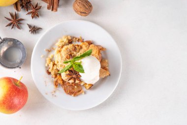  Elmalı gevrek tatlı, dondurmalı çıtır tart, kıtır kıtır hamurlu turta fırın tabağında ve tabakta, dondurma kepçesiyle beyaz mutfak masasında.