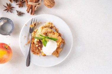  Elmalı gevrek tatlı, dondurmalı çıtır tart, kıtır kıtır hamurlu turta fırın tabağında ve tabakta, dondurma kepçesiyle beyaz mutfak masasında.