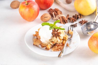  Elmalı gevrek tatlı, dondurmalı çıtır tart, kıtır kıtır hamurlu turta fırın tabağında ve tabakta, dondurma kepçesiyle beyaz mutfak masasında.