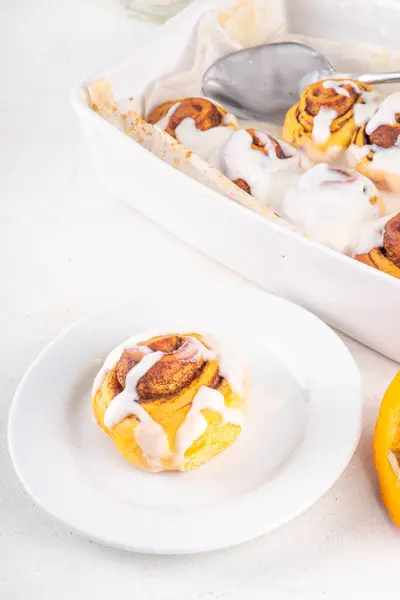 stock image Homemade sweet autumn pumpkin cinnamon swirled bun rolls, pumpkin cinnabons with pecan nuts, cinnamon and creamy cheese icing