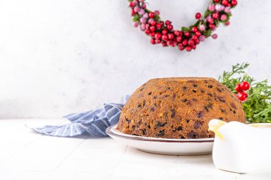 Geleneksel Noel İngiliz pudingi tatlısı. Ev yapımı meyveli puding, kremalı anglaz. Noel için tatlı aromalı meyveli pasta, yeni yıl yemeği, süslü arka planda.