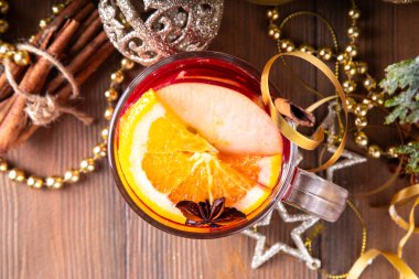 Tatlı elma, portakal, bal, tarçın ve anason yıldızlı cam bardak, ahşap masa üzerinde Noel süsü, tatil içkisi. Sıcak baharatlı amber çayı, alkolsüz sıcak içecek.