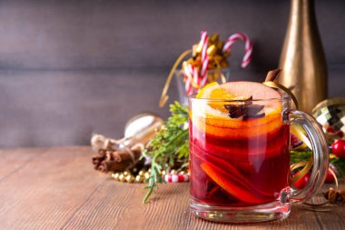 Tatlı elma, portakal, bal, tarçın ve anason yıldızlı cam bardak, ahşap masa üzerinde Noel süsü, tatil içkisi. Sıcak baharatlı amber çayı, alkolsüz sıcak içecek.