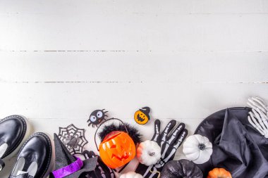 Çocukların Cadılar Bayramı partisi için hazırlıklar, şeker mi şaka mı geleneği. Geleneksel çocuk Cadılar Bayramı kostümlü cadı, hayalet, iskelet, balkabağı aksesuarları, şeker kovası, beyaz arka planda dekor.