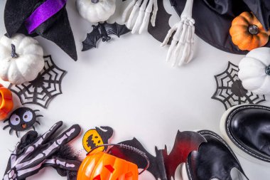 Çocukların Cadılar Bayramı partisi için hazırlıklar, şeker mi şaka mı geleneği. Geleneksel çocuk Cadılar Bayramı kostümlü cadı, hayalet, iskelet, balkabağı aksesuarları, şeker kovası, beyaz arka planda dekor.