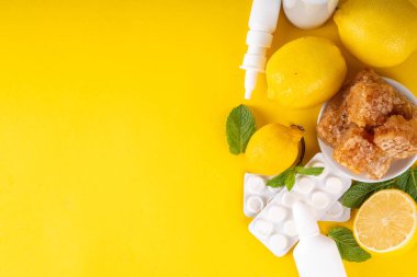 Soğuk algınlığı ve sonbahar mevsimi konsepti, geleneksel ve alternatif soğuk algınlığı ve grip tedavileri, haplar, akan burun, limon, bal ve parlak sarı arka planda nane şekeri için damlalar.