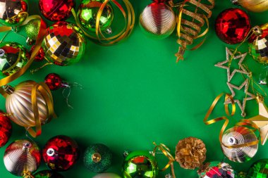 Parlak yeşil yeni yıl arkaplanı, kırmızı, yeşil, altın kostüm topları, flamalar ve süslemeler, üst görünüm fotokopi alanı. Noel ve Yeni Yıl tebrik kartı düzleştirildi