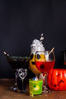 Cadılar Bayramı partisinin şenlik içeceği, çeşitli renkli içkiler, alkolsüz kokteyller, Cadılar Bayramı karakterleriyle içkiler, kostümler, tatil dekorları ve semboller.