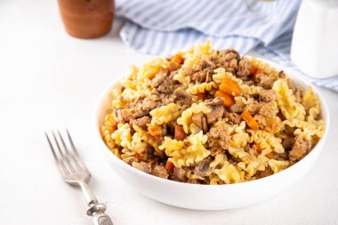 Kıymalı ev yapımı makarna. Biftek ve sonbahar sebzeli bir çömlek makarna, mutfak masasında porsiyonlu tabakta.