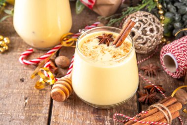 Tarçın çubukları ve anason yıldızlı Noel içeceği Noel 'de iki bardak klasik eggnog kokteyli köknar ağacı ve mücevherlerle süslenmiş yeni yıl arkaplanı.