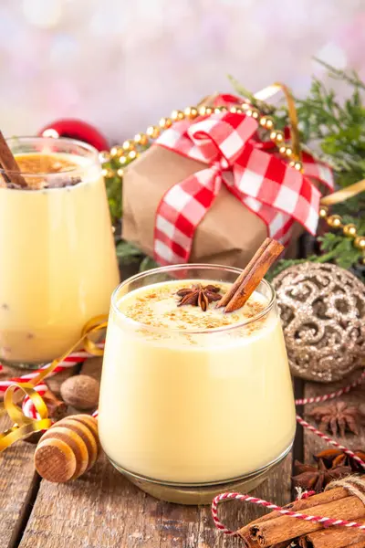 Tarçın çubukları ve anason yıldızlı Noel içeceği Noel 'de iki bardak klasik eggnog kokteyli köknar ağacı ve mücevherlerle süslenmiş yeni yıl arkaplanı.